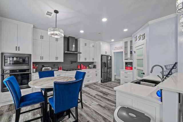 kitchen featuring white cabinets, wall chimney exhaust hood, sink, and stainless steel appliances