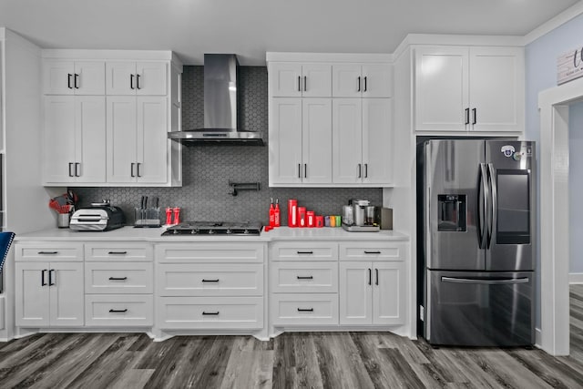 kitchen featuring white cabinetry, wall chimney range hood, and stainless steel fridge