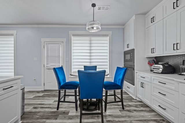 dining room with dark hardwood / wood-style flooring, crown molding, and an inviting chandelier