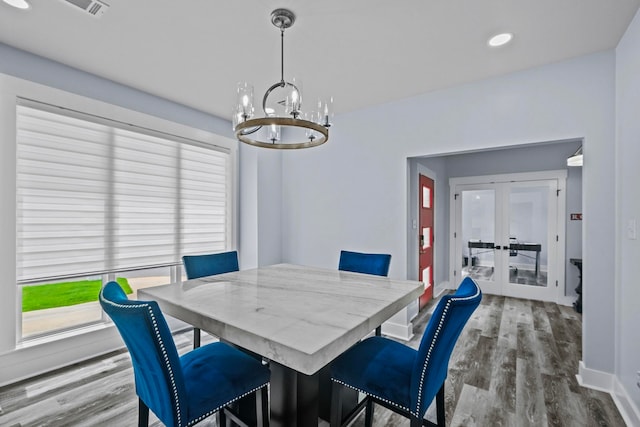 dining space with hardwood / wood-style floors, french doors, and an inviting chandelier