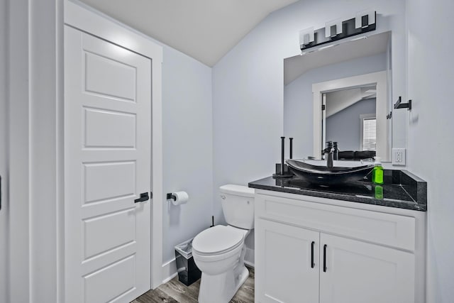 bathroom featuring hardwood / wood-style flooring, toilet, vanity, and vaulted ceiling