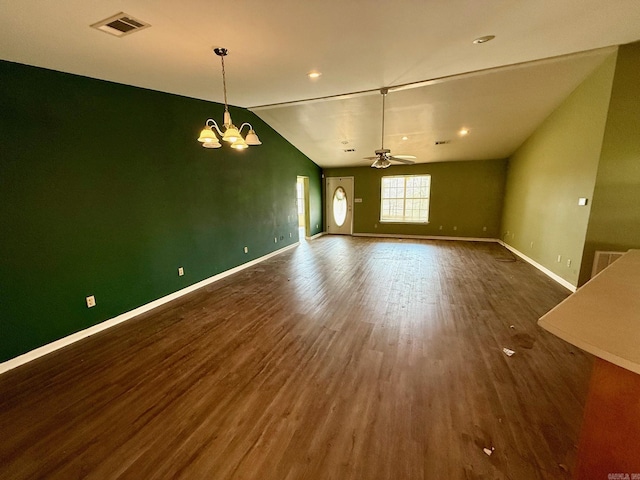 empty room with ceiling fan with notable chandelier, dark hardwood / wood-style flooring, and vaulted ceiling