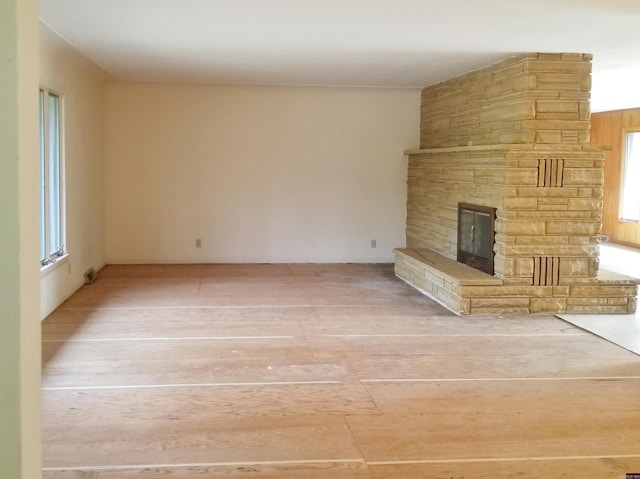 unfurnished living room with a stone fireplace and hardwood / wood-style floors