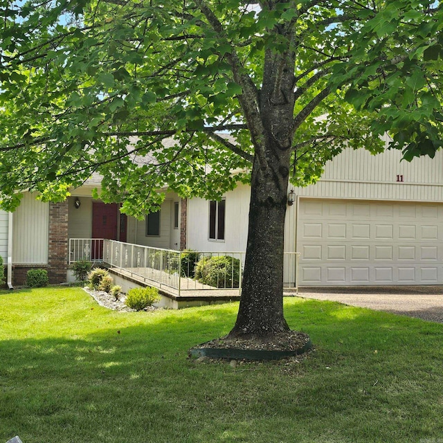 view of property hidden behind natural elements with a garage and a front yard