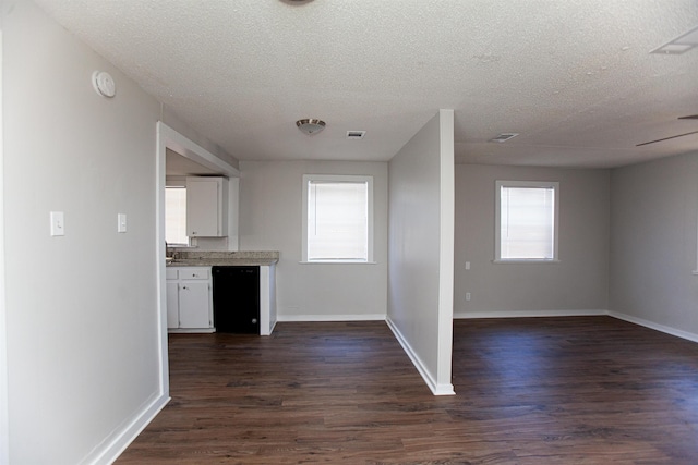 kitchen featuring black dishwasher, plenty of natural light, dark wood-type flooring, a textured ceiling, and white cabinets