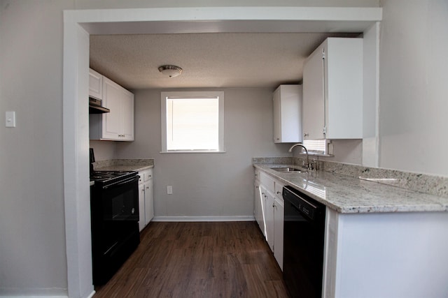 kitchen with light stone countertops, white cabinets, black appliances, sink, and range hood