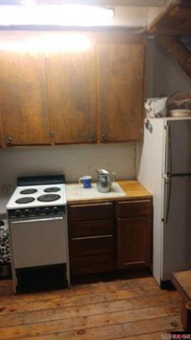 kitchen with white electric range, hardwood / wood-style flooring, and stainless steel fridge