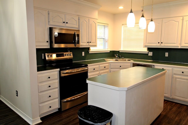 kitchen with sink, appliances with stainless steel finishes, white cabinetry, hanging light fixtures, and a kitchen island