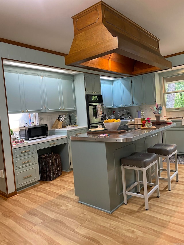 400 Neill Rd, Helena, AR 72342 - kitchen featuring a breakfast bar area, custom range hood, stainless steel appliances, light hardwood / wood-style floors, and decorative backsplash