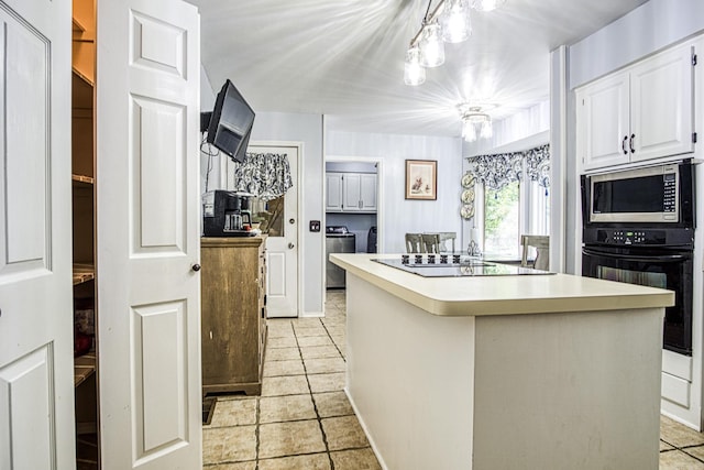 kitchen with washer and clothes dryer, black appliances, a kitchen island, decorative light fixtures, and white cabinetry