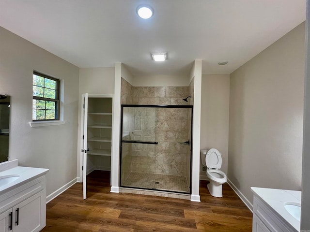 full bathroom with two vanities, wood finished floors, and baseboards