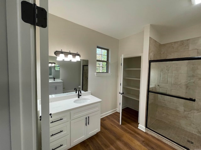 bathroom with a stall shower, wood finished floors, vanity, and baseboards