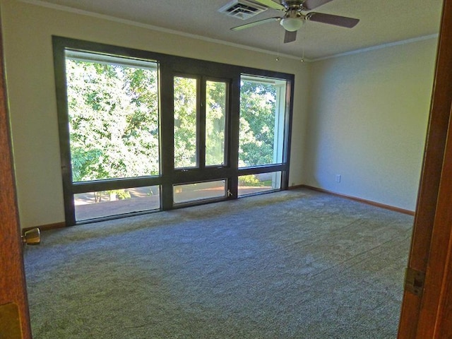 carpeted spare room with baseboards, a ceiling fan, visible vents, and crown molding