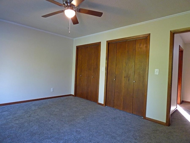 unfurnished bedroom featuring ceiling fan, baseboards, multiple closets, ornamental molding, and carpet