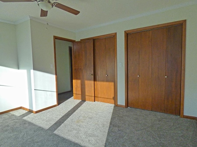 unfurnished bedroom with carpet, multiple closets, ornamental molding, a ceiling fan, and baseboards