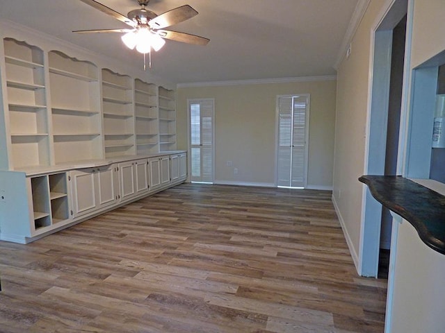 empty room featuring baseboards, dark wood finished floors, a ceiling fan, and crown molding