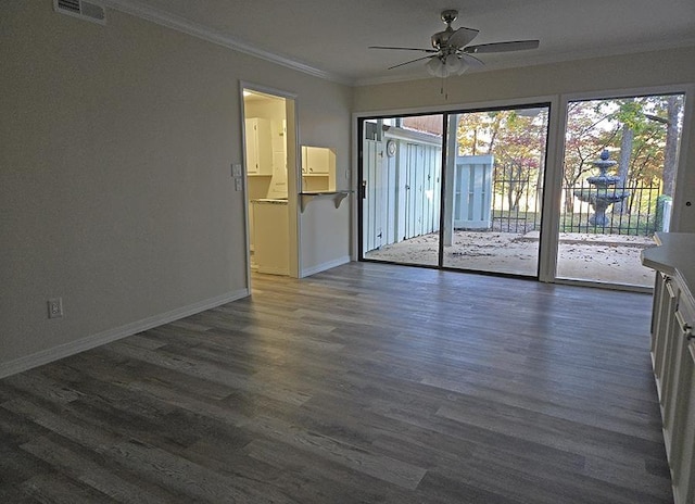 empty room with visible vents, ornamental molding, dark wood-type flooring, ceiling fan, and baseboards