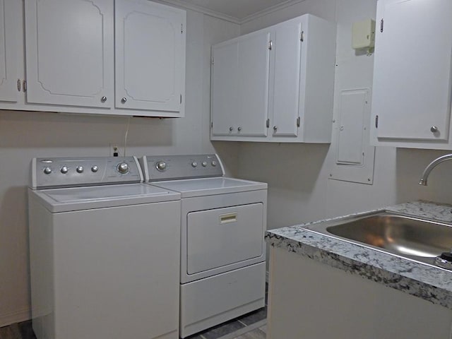 laundry area with cabinet space, separate washer and dryer, and a sink