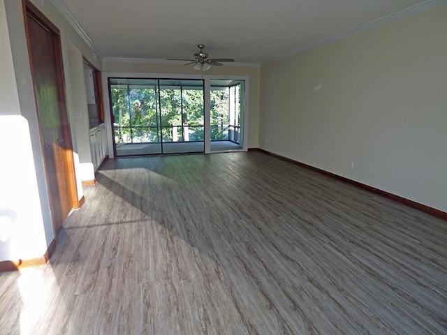 empty room with baseboards, wood finished floors, and crown molding