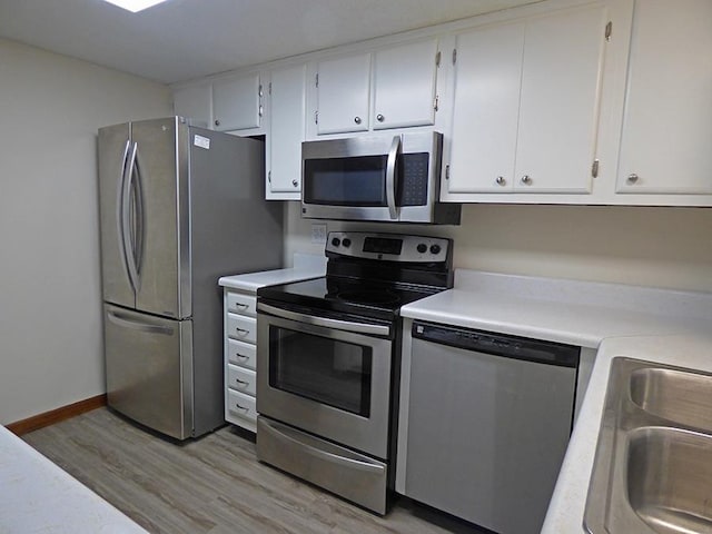 kitchen featuring light countertops, appliances with stainless steel finishes, white cabinetry, a sink, and light wood-type flooring