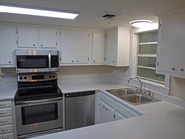 kitchen featuring a textured ceiling, stainless steel appliances, a sink, visible vents, and white cabinets