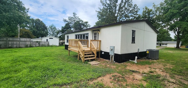 back of house with cooling unit, a wooden deck, and a yard