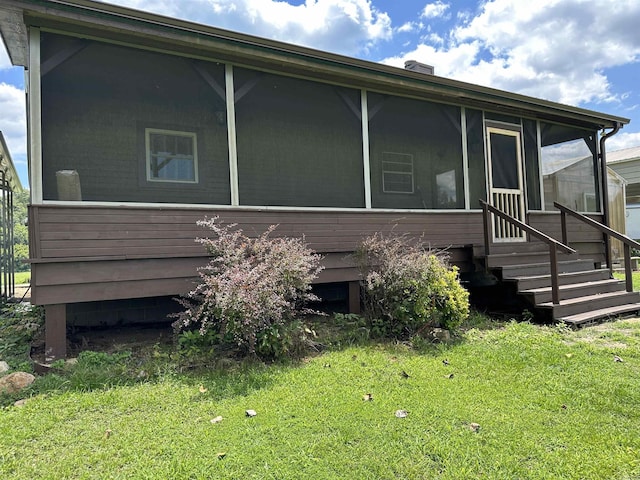 exterior space with entry steps, a sunroom, and a lawn