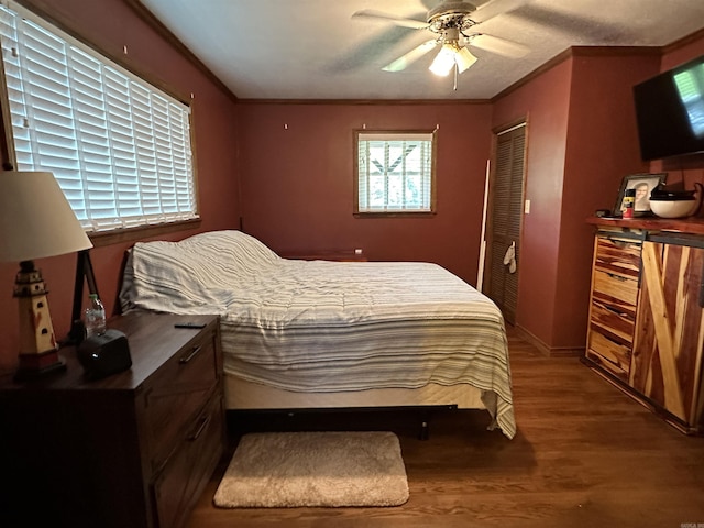 bedroom with baseboards, ceiling fan, ornamental molding, wood finished floors, and a closet