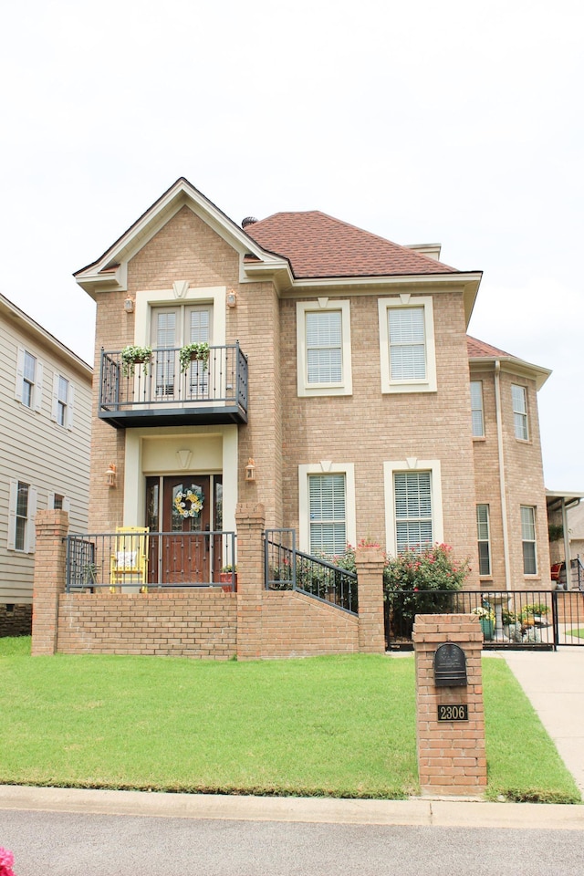 view of front facade featuring a balcony and a front yard