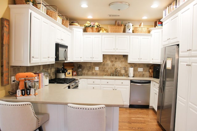 kitchen featuring decorative backsplash, a breakfast bar, appliances with stainless steel finishes, and kitchen peninsula