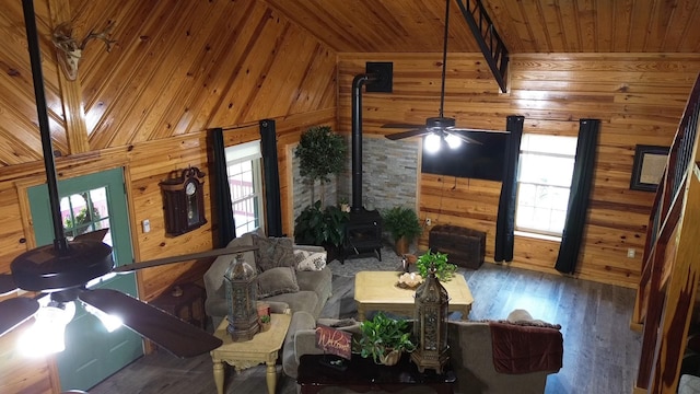 living room featuring beamed ceiling, wooden walls, dark wood-type flooring, wood ceiling, and a wood stove