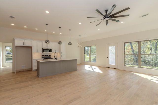 kitchen with stainless steel appliances, visible vents, backsplash, light wood-style floors, and white cabinetry