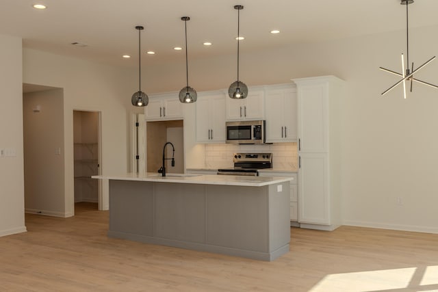 kitchen featuring white cabinets, decorative backsplash, stainless steel appliances, and a sink