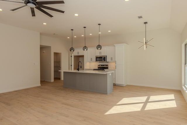 kitchen featuring stainless steel appliances, a sink, visible vents, white cabinets, and tasteful backsplash