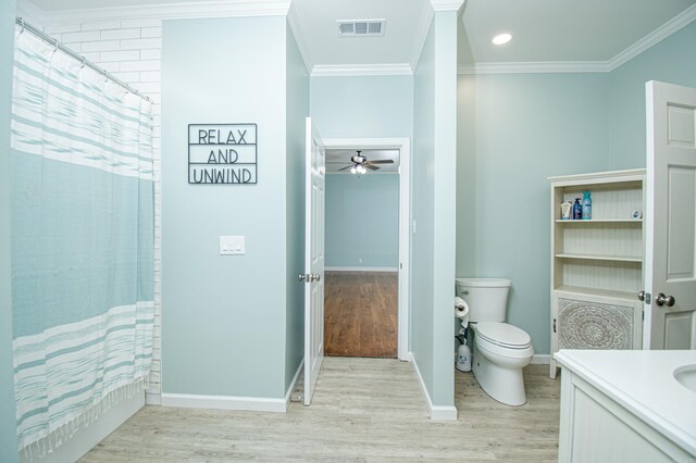 bathroom with crown molding, toilet, vanity, ceiling fan, and wood-type flooring