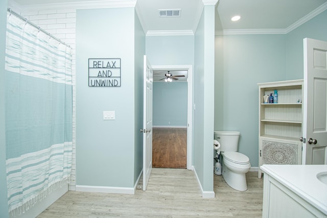 bathroom featuring toilet, wood finished floors, visible vents, baseboards, and ornamental molding