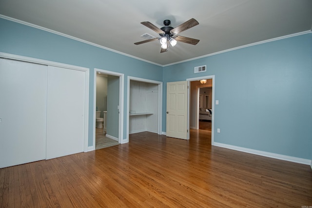 unfurnished bedroom with visible vents, ornamental molding, connected bathroom, wood finished floors, and baseboards