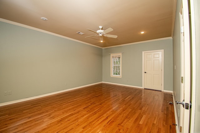 spare room featuring light wood-style floors, visible vents, crown molding, and baseboards