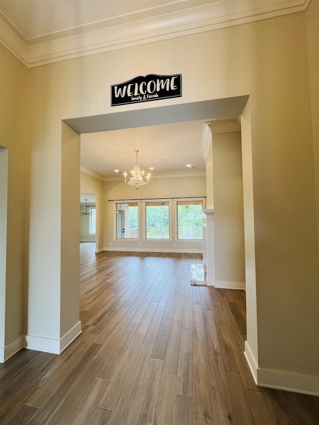 unfurnished living room with crown molding, hardwood / wood-style floors, and a notable chandelier