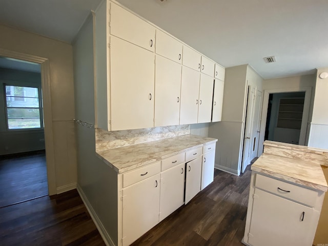 kitchen with dark wood-style floors, visible vents, white cabinetry, and light countertops