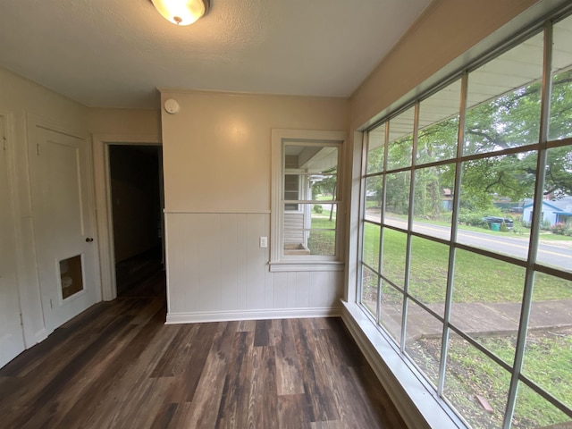 empty room featuring dark wood-style floors, a wainscoted wall, and a textured ceiling