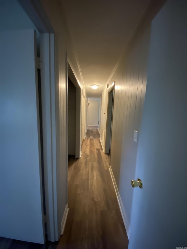 hall with dark wood-style floors, baseboards, and ornamental molding