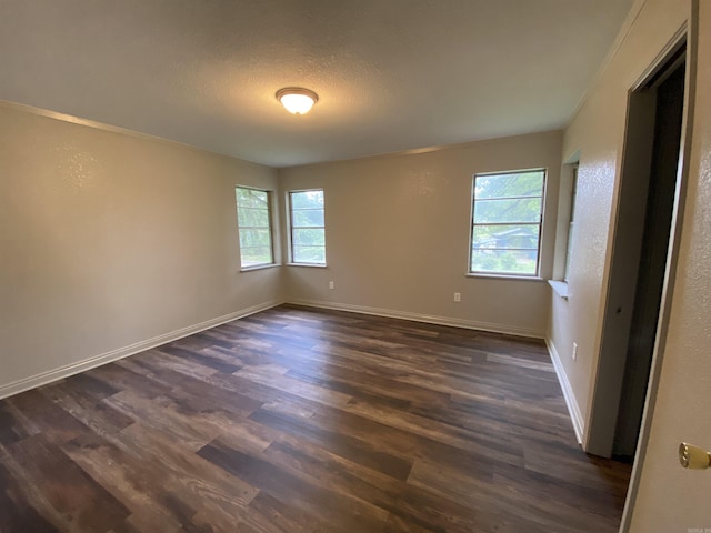 spare room with baseboards, a textured ceiling, and dark wood finished floors