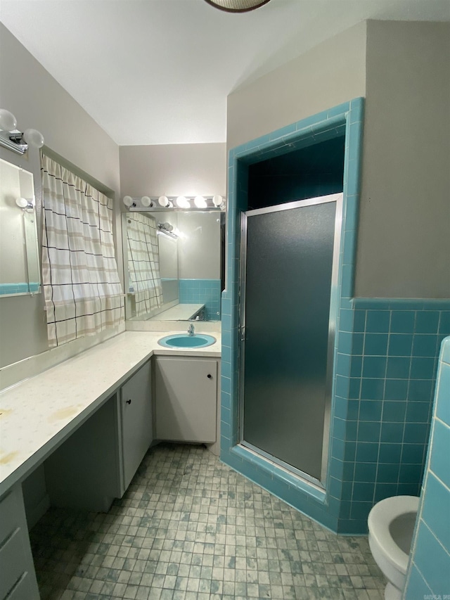 bathroom featuring wainscoting, a shower stall, tile walls, and vanity