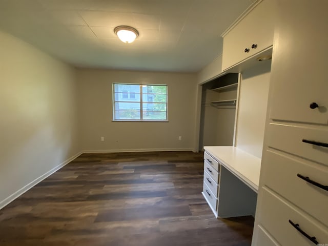 unfurnished bedroom with dark wood-style floors, baseboards, and a closet