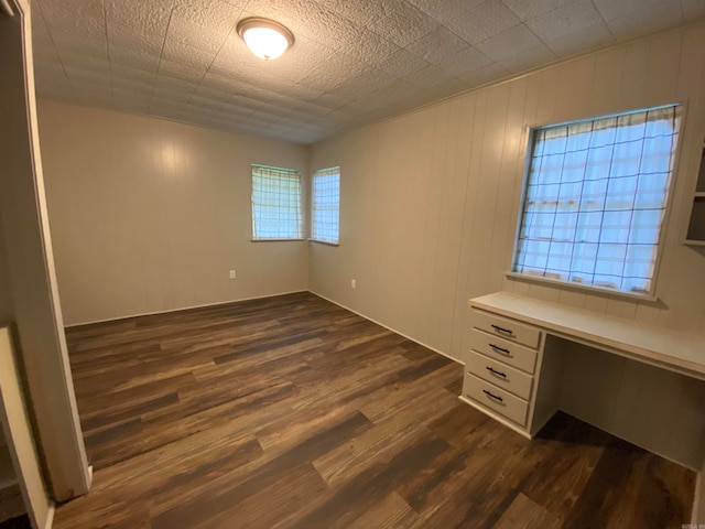 empty room with dark wood-type flooring and built in desk