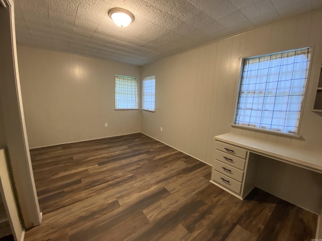 unfurnished bedroom with dark wood-type flooring and built in desk