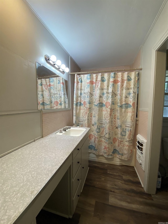 bathroom with toilet, ornamental molding, heating unit, wood finished floors, and vanity