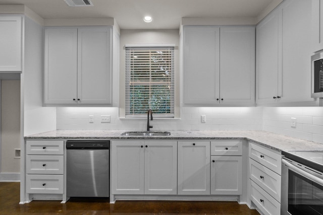 kitchen featuring appliances with stainless steel finishes, tasteful backsplash, sink, white cabinets, and light stone counters