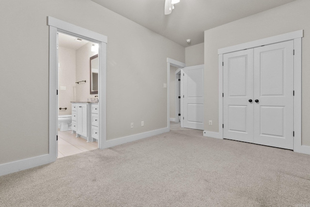 unfurnished bedroom featuring connected bathroom, light colored carpet, ceiling fan, and a closet